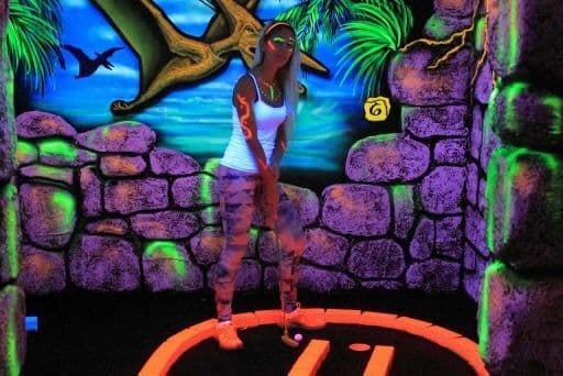 Woman playing 3D blacklight mini golf at Wild Fun Zone